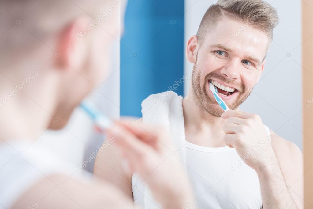 Young fashionable man brushing teeth