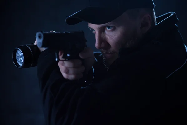 Policeman holding gun and flashlight — Stock Photo, Image