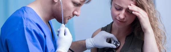 Médico con estetoscopio examinando mujer — Foto de Stock