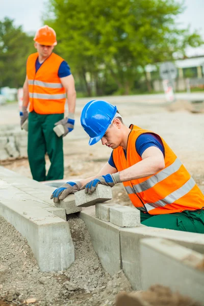 Ouvrier de la construction pose pavés — Photo