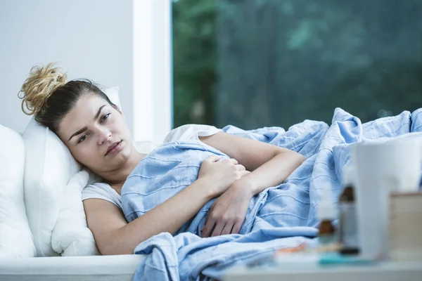 Άρρωστη γυναίκα ξαπλωμένη στο κρεβάτι — Φωτογραφία Αρχείου