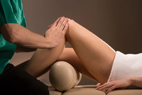 Massagetherapeutin streichelt weibliche Beine — Stockfoto