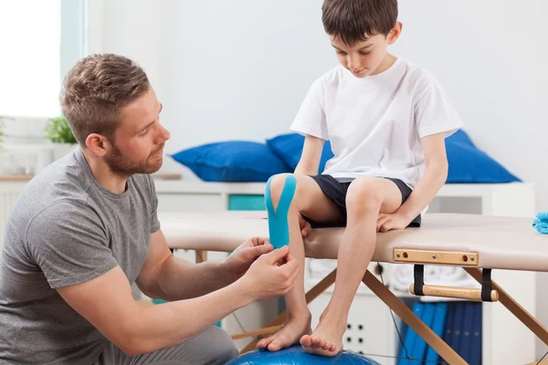 Terapeuta pegando cinta de kinesiología — Foto de Stock