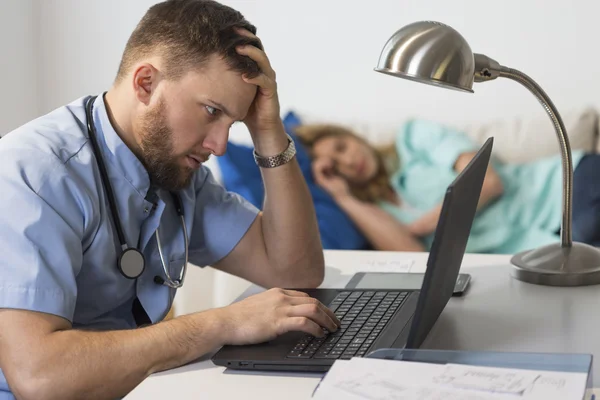 Medico oberato di lavoro seduto al computer — Foto Stock