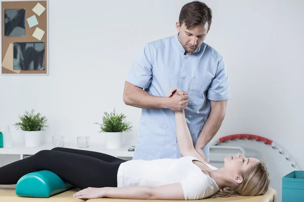 Knappe fysiotherapeut werken met patiënt — Stockfoto