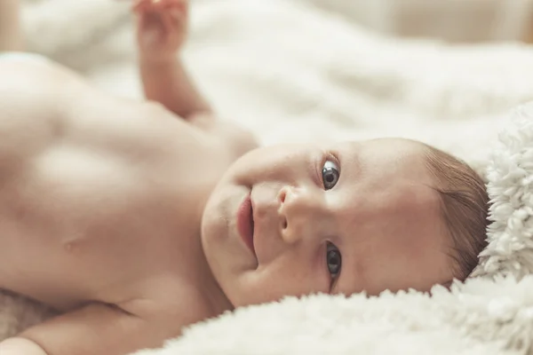 Bambino sorridente sdraiato sulla coperta — Foto Stock