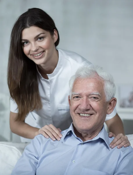 Jonge verpleegster bezoeken oudere man — Stockfoto