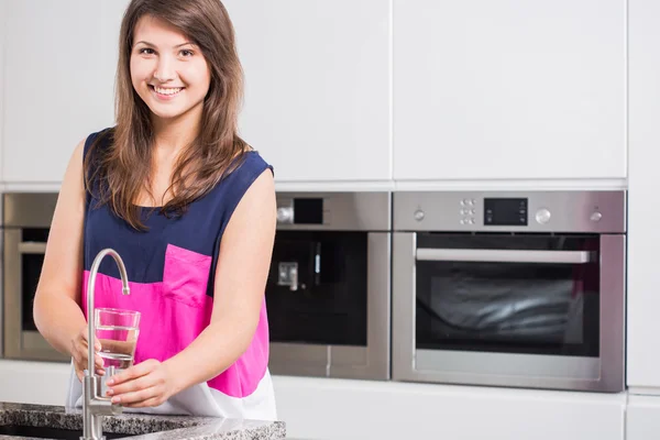 Giovane donna versando acqua del rubinetto — Foto Stock