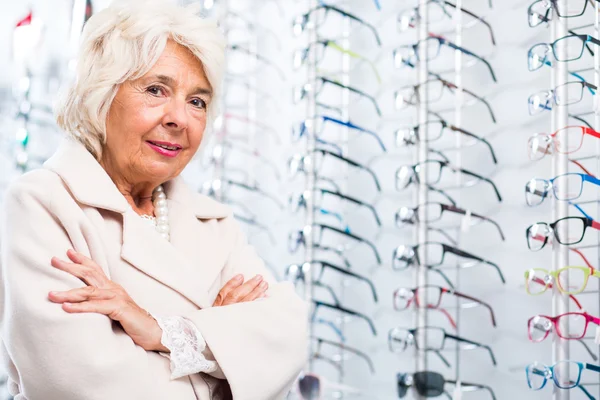 Äldre kvinna i optiker butik — Stockfoto