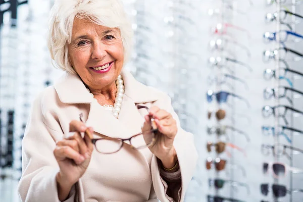 Vrouwelijke gepensioneerde in opticien winkel — Stockfoto