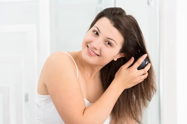 Mulher penteando seu cabelo longo — Fotografia de Stock