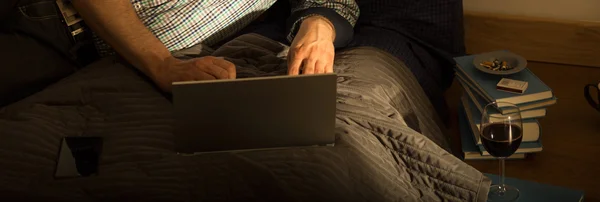 Άνθρωπος χρησιμοποιώντας φορητό υπολογιστή στο κρεβάτι — Φωτογραφία Αρχείου