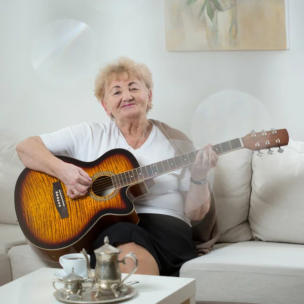 Старшая женщина играет на гитаре — стоковое фото