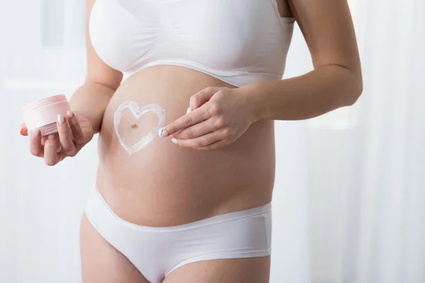 Mulher grávida aplicando bálsamo corporal — Fotografia de Stock
