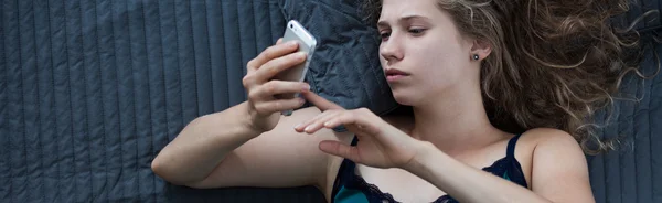 Frau schreibt SMS im Bett — Stockfoto