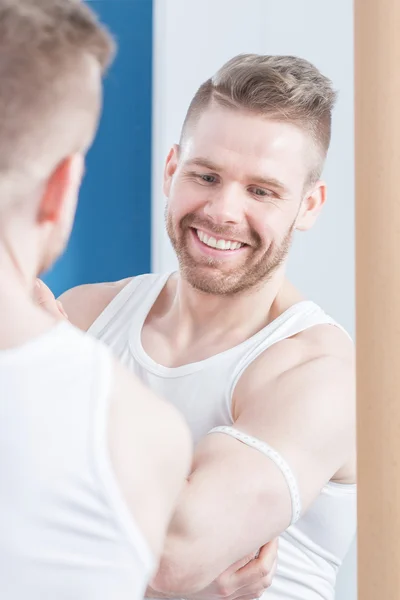 Aantrekkelijke bodybuilder meten zijn biceps — Stockfoto