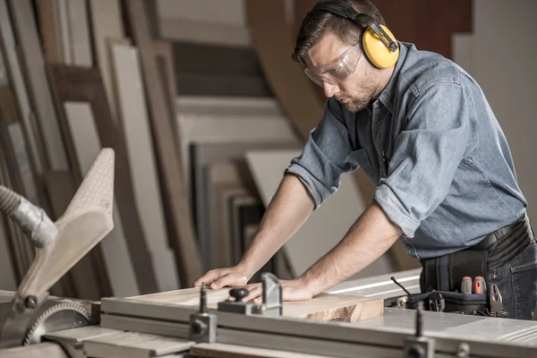 Carpenter cutting wood on workbench — Stock Photo, Image