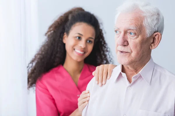 Female carer assisting senior man — Stock Photo, Image