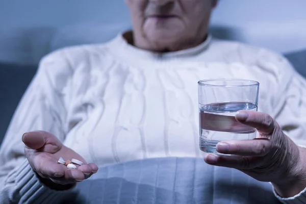 Mulher segurando pílulas e água — Fotografia de Stock