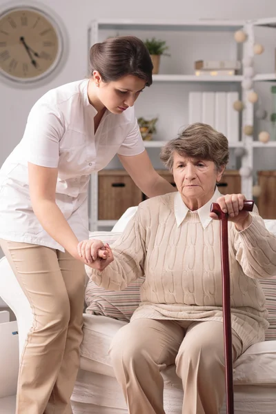 Carer helping senior with stick — Stock Photo, Image