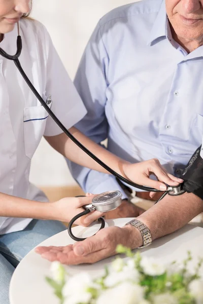 Nurse measuring patient's blood pressure — Stock Photo, Image