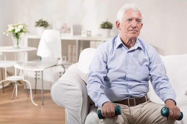 Elderly man sitting with dummbells — Stock Photo, Image