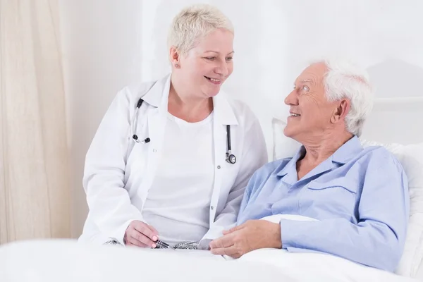 Enfermera sonriendo a su paciente mayor — Foto de Stock