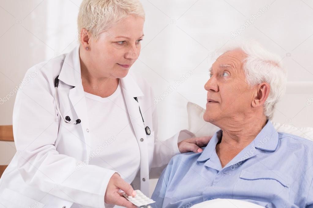 Nurse giving pills to senior patient