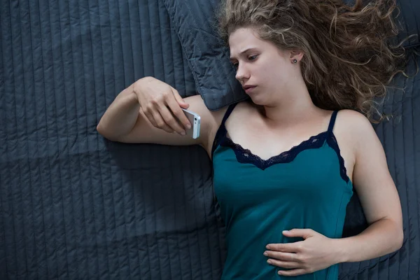 Uso del teléfono móvil en la cama — Foto de Stock