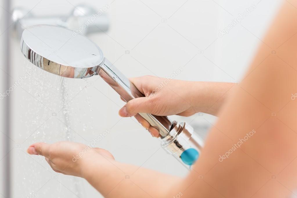 Female hands holding hand shower