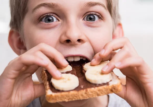 Boy eating sandwich with chocolate — Stock Photo, Image