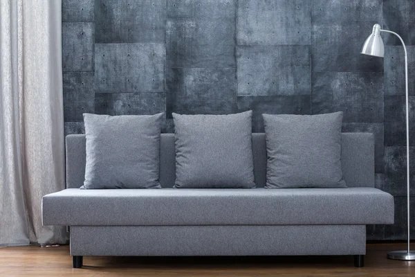 Sofa on concrete wall — Stock Photo, Image