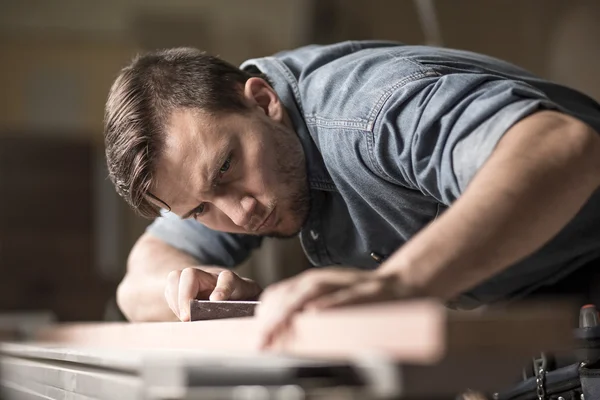 Joinery worker smoothening wood piece — Stock Photo, Image