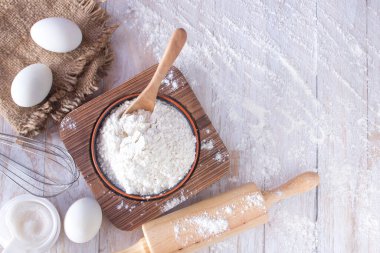 Ev yapımı un tarifleri (yumurta, un, şeker) ve ahşap bir masa üzerinde yuvarlak pin, yukarıdan görünüm
