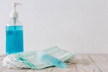 Anti-Covid-19-Coronavirus maskesi ve beyaz ahşap masaya el jölesi.