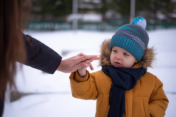 Moskova - 11 Aralık 2020: Anne kışın çocuğuyla birlikte yürür, bebeği elinden tutar ve bebek anneye bakar.