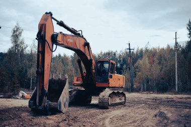 Dmitrov, Rusya - 12 Eylül 2021: Bir Hitachi kazıcısı bir ormanda çalıştıktan sonra bir kum havuzunda elinde kovayla duruyor.