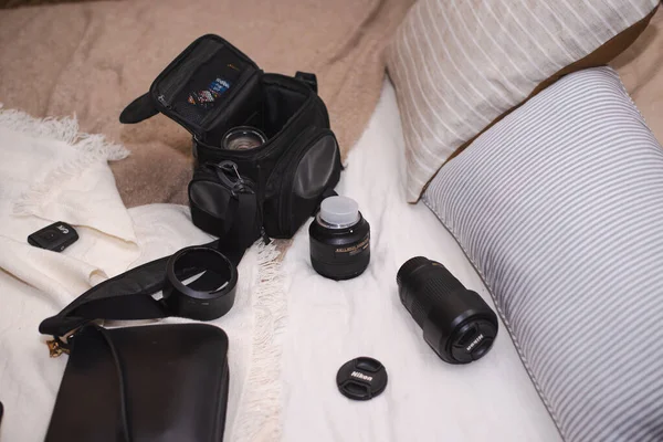 Dmitrov, Rusya - 19 Eylül 2021: Düzensiz bir yatakta, fotoğraflı eşyalar, çantada bir kamera ve iki Nikon lensi var.