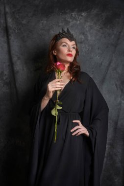 Siyah elbiseli kadın, kırmızı gül ve siyah arka plan.