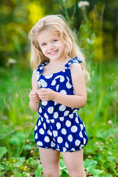 Красивая улыбающаяся маленькая девочка с длинными светлыми вьющимися волосами — стоковое фото