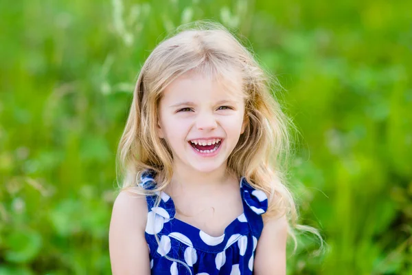 Милая смеющаяся маленькая девочка с длинными светлыми вьющимися волосами — стоковое фото