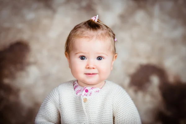 Petite fille blonde étonnée avec de grands yeux gris et des joues dodues. Portrait studio sur fond marron grunge — Photo