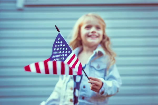 Amerikaanse vlag in kleine meisje hand. Selectieve aandacht, onscherpe achtergrond. De dag van de onafhankelijkheid, dag van de vlag concept. Vintage en retro toning. Instagram filters Stockfoto