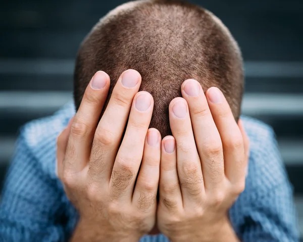 Closeup portret van ontredderde jonge man die betrekking hebben op zijn gezicht met handen. Selectieve aandacht op handen. Verdriet, wanhoop, tragedie concept — Stockfoto