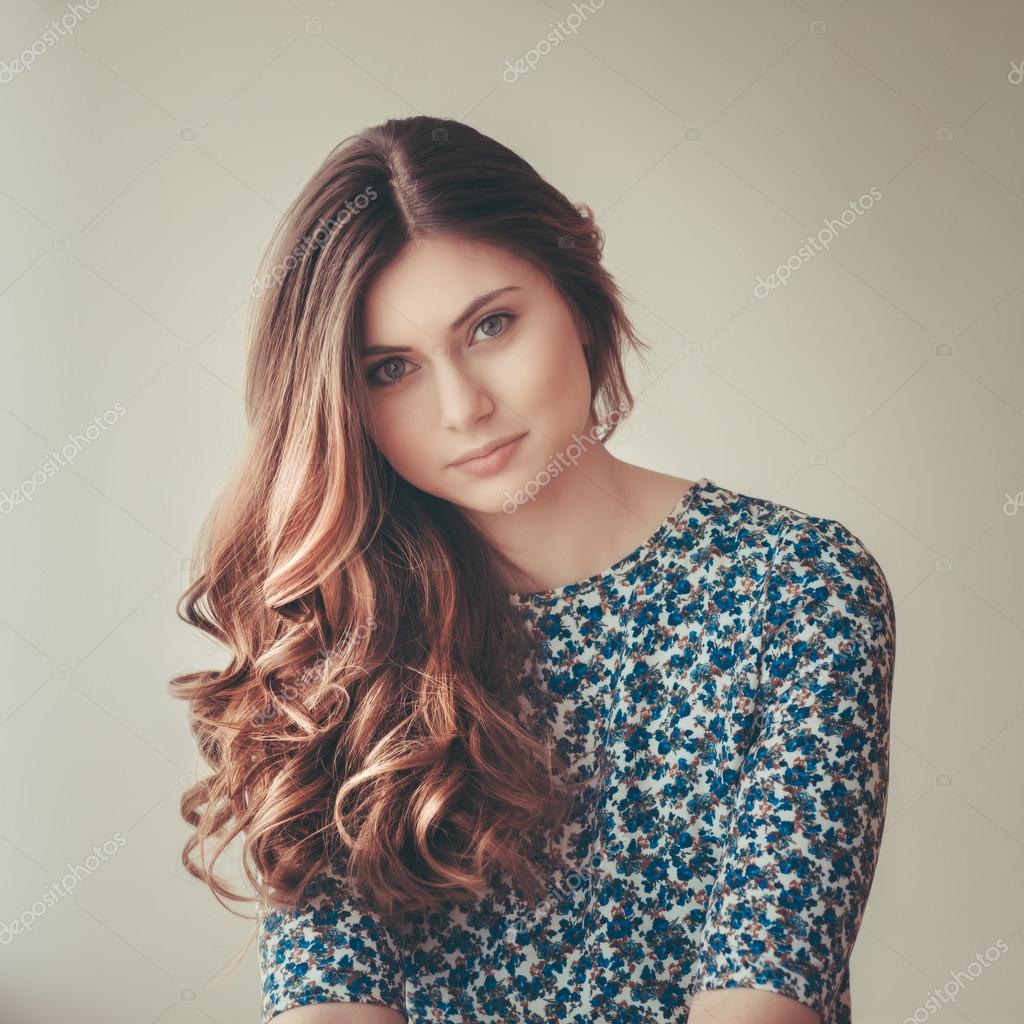 Beautiful young woman with long curly red hair, indoor portrait with