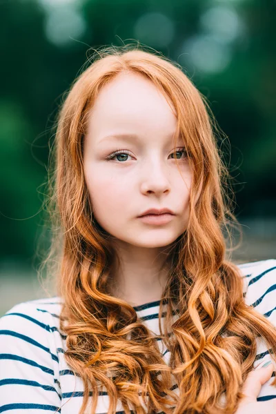 A beautiful girl with green eyes and long curly red hair in summer park. Outdoor portrait of a red-haired teenage girl. Adorable young redhead longhaired woman — Stock Photo, Image