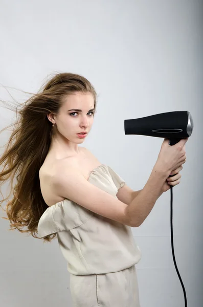 A menina brinca com o secador de cabelo com o cabelo — Fotografia de Stock