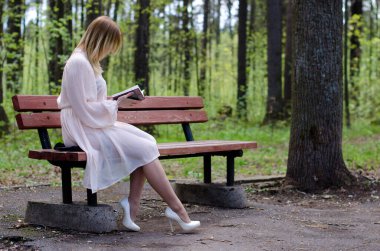 Parktaki genç kız elinde bir kitapla