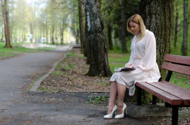 Parktaki genç kız elinde bir kitapla