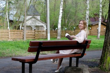 Parktaki genç kız elinde bir kitapla